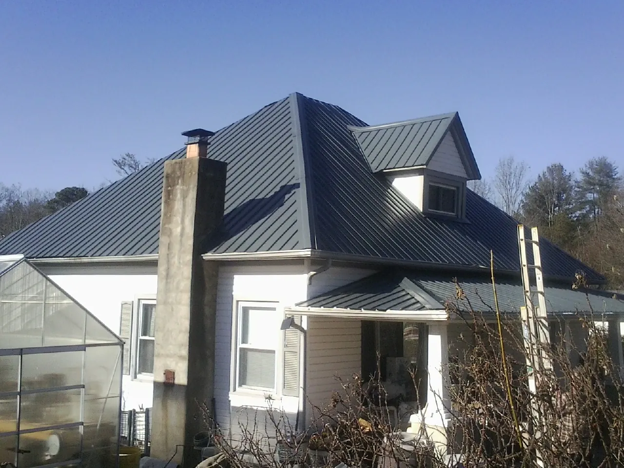Dark blue standing seam metal roof on a white farmhouse with dormer — Slate & Tile Roof Repair by Roofing Brothers in Bosque Farms