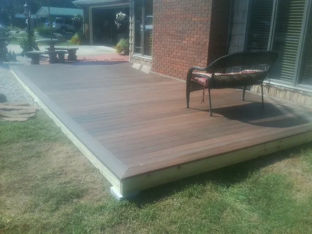 New wood deck and wicker chair beside a brick house in Bosque Farms
