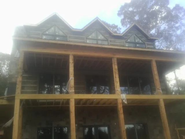 Dormers and porch framing on a large log home under construction — Roof Coating work by our crew in Bosque Farms