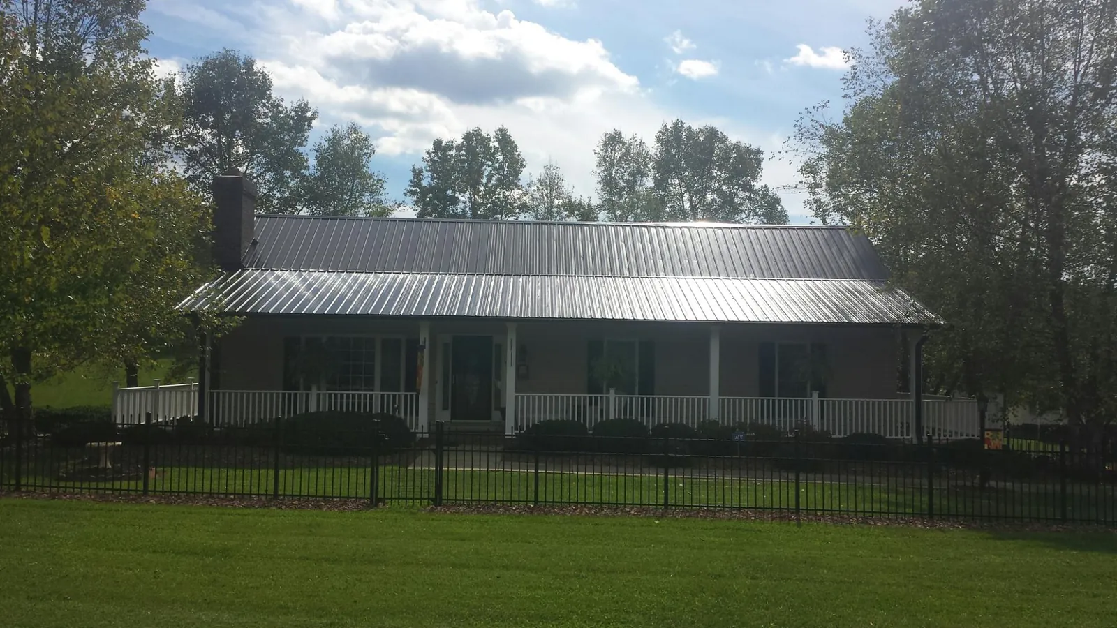 Gray metal roof on a brick ranch with a full width front porch — Gutter Guard Installation work by our crew in Bosque Farms