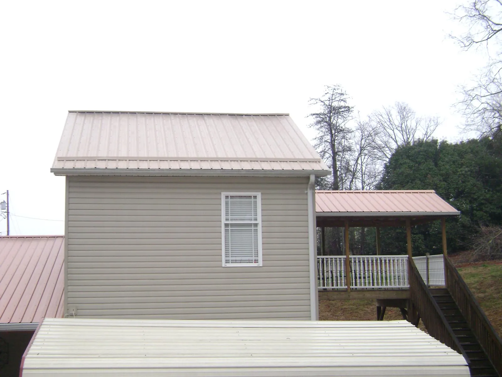 Tan metal roofs on a two story addition and attached porch, from a Roof Replacement job in Bosque Farms